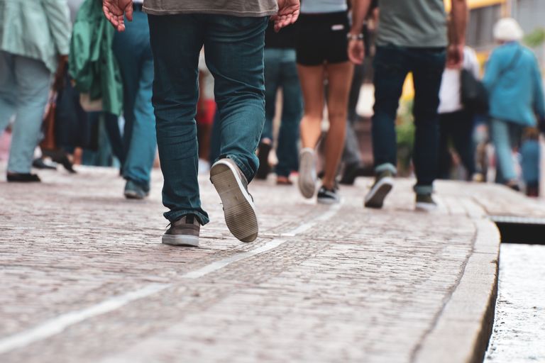 A diverse group of individuals walking on a cobblestone street, showcasing urban daily life.
