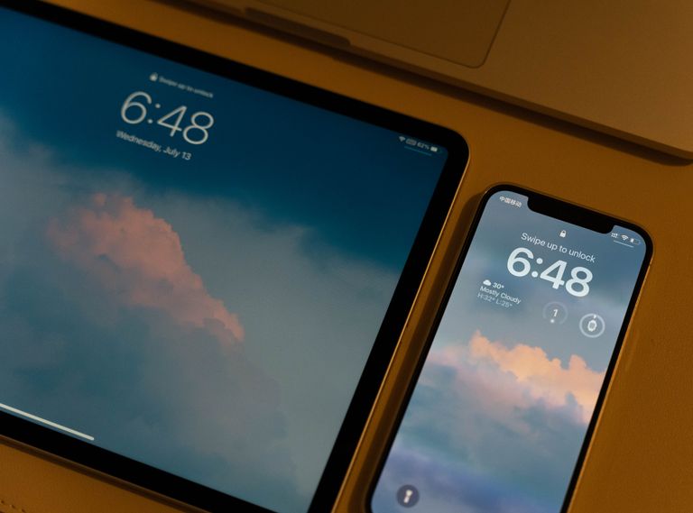 Close-up of modern digital devices with cloud-themed wallpaper and lock screens.