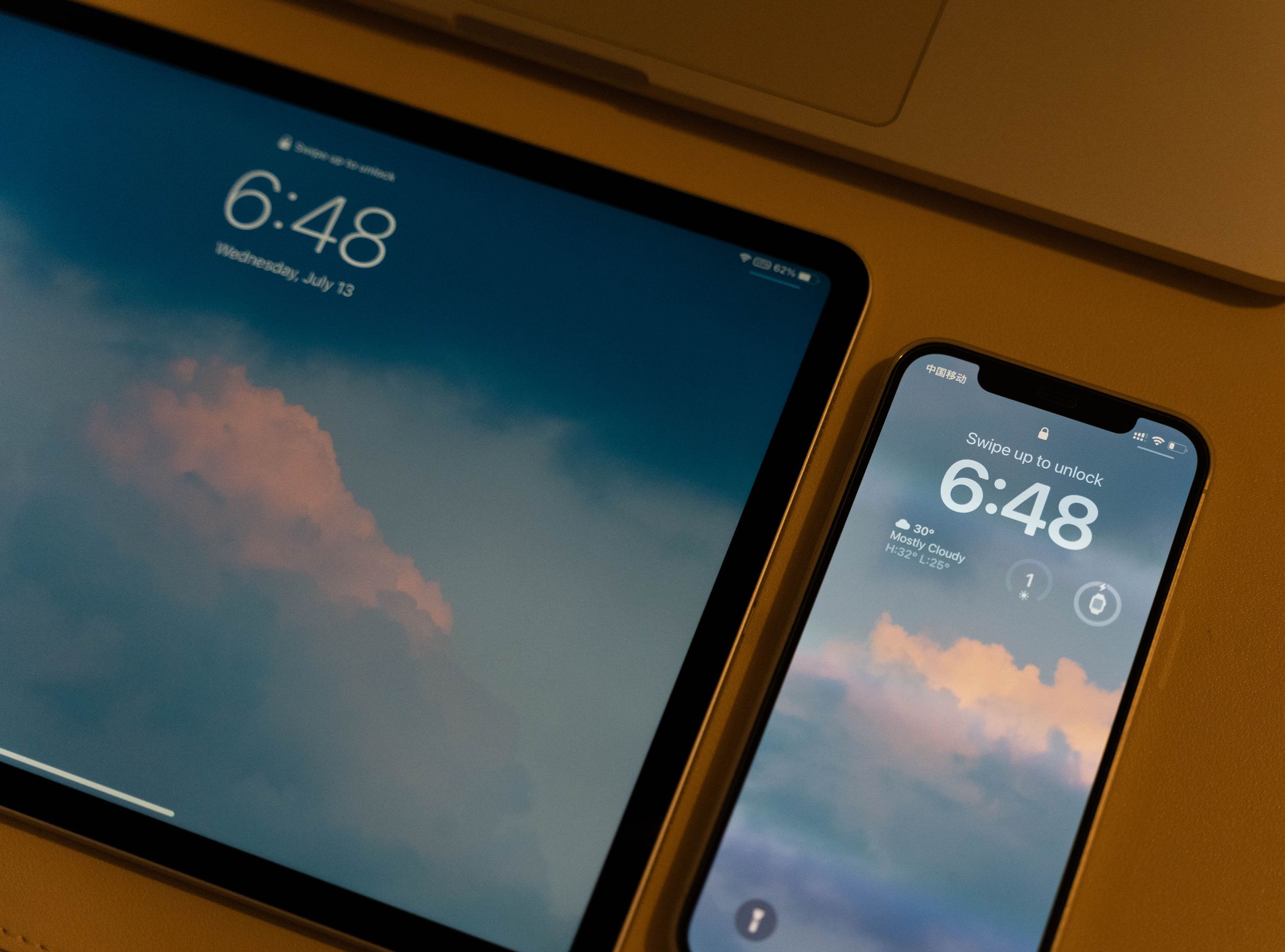 Close-up of modern digital devices with cloud-themed wallpaper and lock screens.