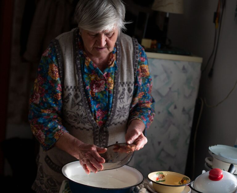 Elderly woman preparing food in a homely kitchen setting, showcasing traditional cooking style.