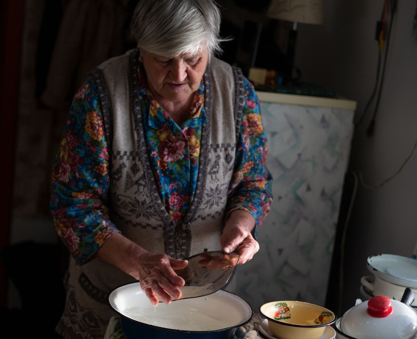 Elderly woman preparing food in a homely kitchen setting, showcasing traditional cooking style.