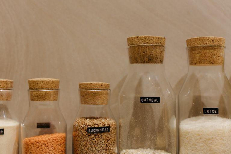 Close-up of various grains in labeled glass jars for kitchen storage.
